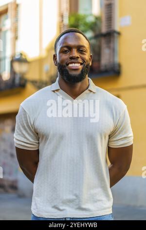 Vertical portrait of an african man with hands on back smiling at camera in the street Stock Photo