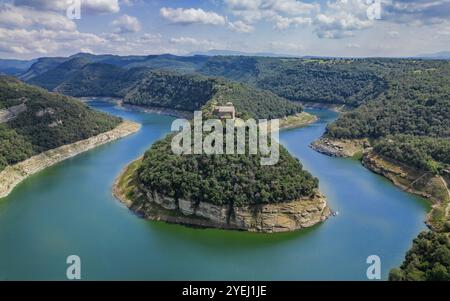 Aerial view of a river winding through lush, forested hills and rocky cliffs under a partly cloudy blue sky, River Ter meander, Catalonia, Spain, Euro Stock Photo