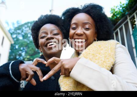 Joyful Friends Making Heart Shape with Hands in the City on a Bright Day Stock Photo