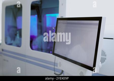Laboratory technicians working on data analysis in a medical lab environment, with several large monitors and equipment in use Stock Photo