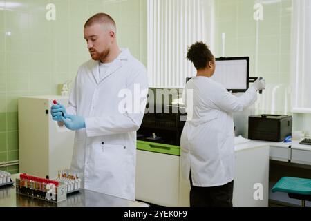 Researchers conducting experiments in laboratory, working with scientific instruments and recording data. Laboratory setup includes advanced analytic tools and organized workspace Stock Photo