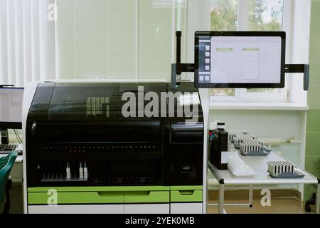 Advanced laboratory setup featuring high-tech machinery and modern gadgets situated next to a window, displaying data on a screen, and arranged for scientific analysis Stock Photo