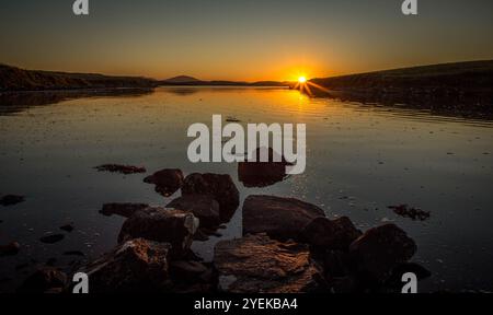 Sun setting over very calm sea Loch Stock Photo