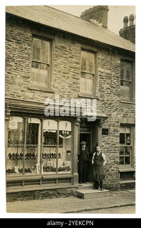 Early 1920's postcard of shopkeepers outside their independent small shop. F. & S. Jones boot and shoe shop is the sign in the shopfront window. These shoe shop propietors are advertising Grenson's designer shoes.  Bristol House, Pembroke, Wales, U.K. Stock Photo