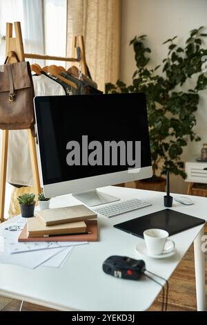 Modern computer and stationery on table with coffee cup in well lit room. Stock Photo