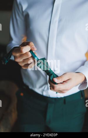 A man holds a stylish green butterfly in his hands. Bow tie for a stylish look. Stock Photo