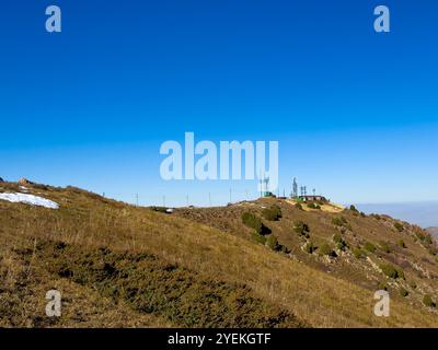 A mountain station on the ridge under a clear blue sky in Kyrgyzstan, with snowy slopes and hills in the background Stock Photo