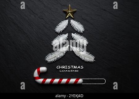 Fir tree and candy cane on black stone background. Minimal Christmas loading concept. Stock Photo