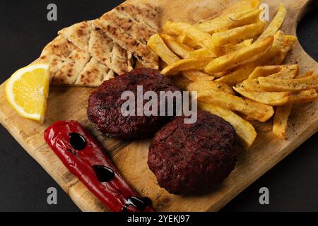 XL beef patty made from minced meat with fried potatoesm, pepper, pita and yogurt dip on wooden board. Stock Photo