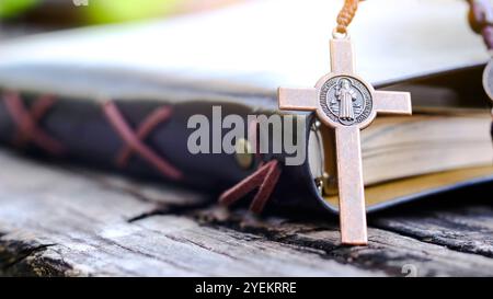 Dark red copper cross leaning against an old open book symbolizing the spread of Jesus Christs love among Christians reflecting faith devotion and the Stock Photo