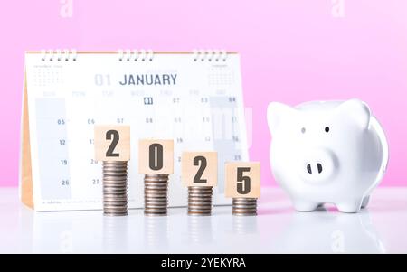 Stack of coins beside a wooden block labeled '2025' and a calendar. Symbolizes financial planning for the upcoming year, emphasizing budgeting and set Stock Photo
