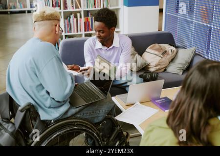 Two colleagues working together on project while seated at table with laptops and documents. Engaging in teamwork and collaboration in a modern office setting Stock Photo
