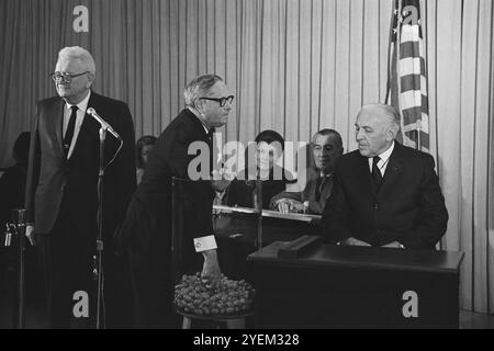 Congressman Alexander Pirnie reaching into a container of draft numbers (center) as others look on, including retiring Selective Service Director Lt. General Lewis Blaine Hershey (left) and Deputy Director Col. Daniel O. Omer (right) at the Selective Service Headquarters during the nationwide draft lottery. USA. 1 December 1969 Stock Photo