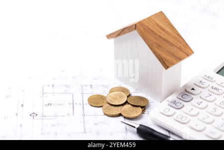 A concept of budgeting for home construction, with a house model, calculator, and construction plans placed on a table, symbolizing financial planning Stock Photo
