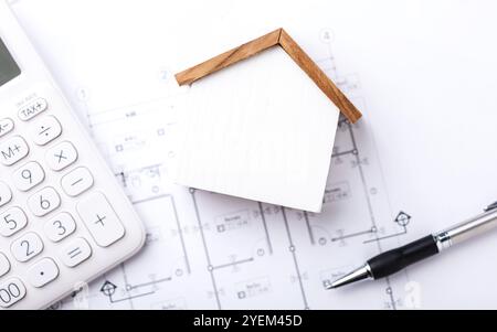 A concept of budgeting for home construction, with a house model, calculator, and construction plans placed on a table, symbolizing financial planning Stock Photo