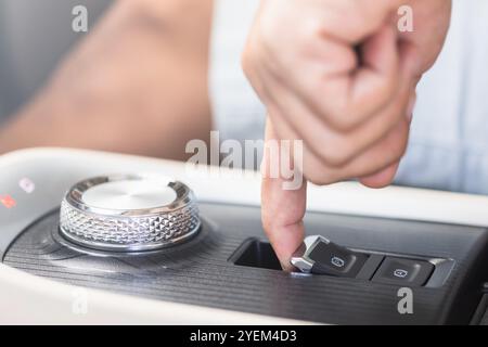 Hand pressing the electric parking brake button in an electric vehicle. Image captures the concept of advanced automotive technology, emphasizing the Stock Photo