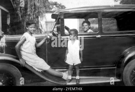 A mother and her children pose with their new car, ca 1930. Stock Photo