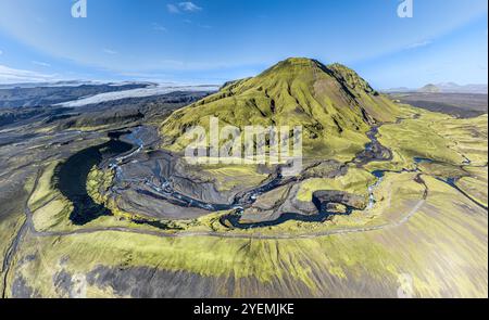 River along road F232 Öldufellsleid, slopes of Mt. Öldufell, moss-covered hill in black lava sand, Mt. Maelifell in the back (right), aerial view, Ice Stock Photo