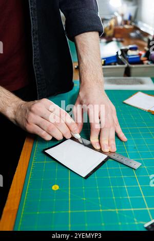 The hands of the master sew handmade leather products. Men's hands connect the parts, creating quality leather accessories. Working process in a leath Stock Photo