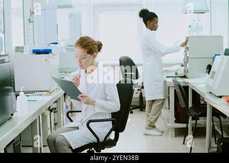 Scientists conducting research in modern laboratory, focused on studying results and adjusting machines, ensuring accuracy in analysis Stock Photo