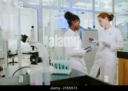 Scientists engaging in lab work, examining samples on slide. Laboratory equipment and intricate procedures evident in workspace Stock Photo