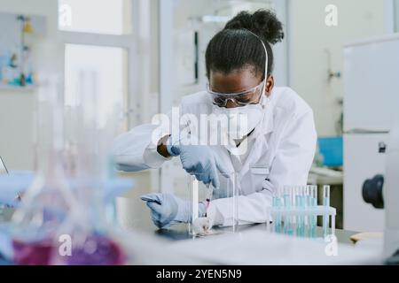Scientist wearing protective gear while conducting scientific experiment in modern laboratory using various lab equipment. Focused on conducting precise measurements Stock Photo