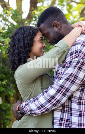 Loving multiracial couple embracing outdoors, smiling and enjoying tender moment together. Romance, affection, happiness, connection, intimacy, tender Stock Photo