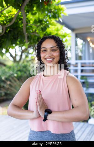 Smiling woman practicing yoga outdoors, enjoying peaceful moment in nature. meditation, wellness, tranquility, mindfulness, relaxation, harmony Stock Photo