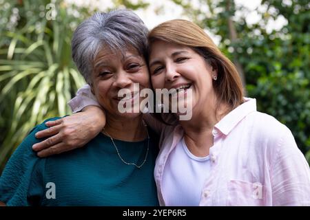 Senior female friends embracing outdoors, smiling and enjoying time together. Friendship, togetherness, happiness, bonding, elderly, female friends Stock Photo