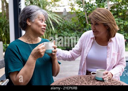 Sharing joyful moments, senior female friends drinking coffee and chatting outside together. Friendship, leisure, conversation, laughter, happiness, c Stock Photo