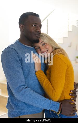 Happy multiracial couple embracing at home, enjoying cozy holiday moments together. romance, love, affection, togetherness, happiness Stock Photo