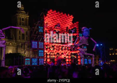 A vibrant Day of the Dead altar with illuminated decorations and skeletons lights up Zócalo at night, celebrating Mexican tradition. Dia de Muertos. Stock Photo