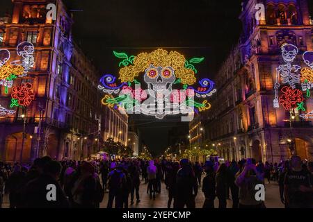 Brightly lit Day of the Dead decorations featuring skulls, flowers, and neon colors illuminate a Avenida 20 de Noviembre in downtown at night. Dia de Stock Photo