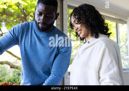 Preparing thanksgiving meal, smiling multiracial couple working together in bright kitchen, at home. cooking, family, celebration, festive, holiday, t Stock Photo