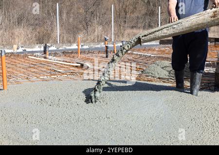 Worker builder pouring concrete from a concrete mixer on a construction site for a slab of a new building Stock Photo