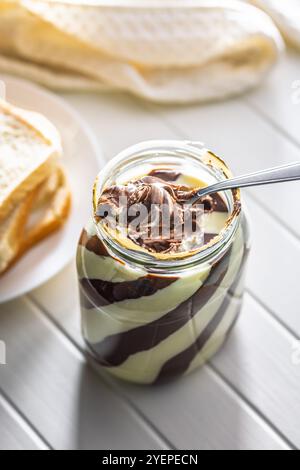 Chocolate cream spread on spoon in a jar. Stock Photo