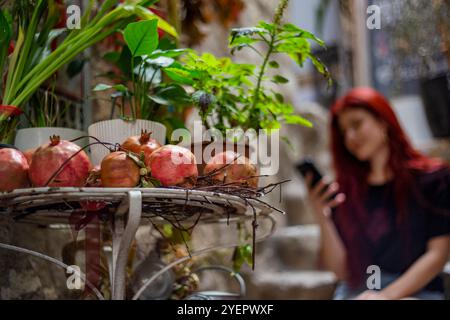 Pomegranates on the table against blurred woman using smartphone Stock Photo