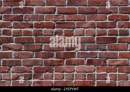Detail of a section of a red brick wall with rows of clay-fired red bricks. Stock Photo