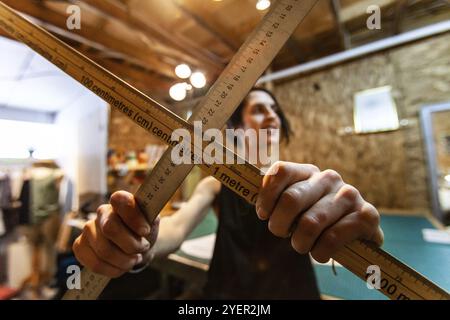 A closeup view of two wood measuring rods being held by a woman tailor inside her retro studio. Artist shows tools used in design process Stock Photo