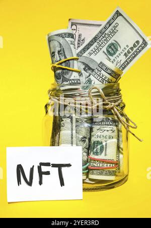 NFT non-fungible token text. Concept words NFT non-fungible token on paper blank. Background of dollar bills. Blockchain asset crypto art, digital art Stock Photo