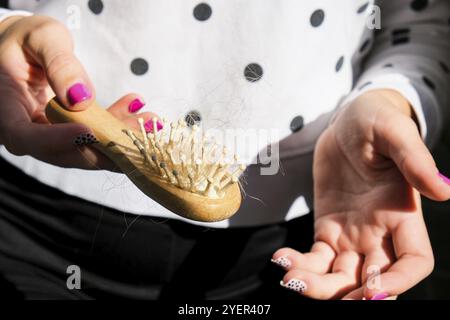 Hand holds bunch of hair on the comb. Hair loss concept. Female seasonal hair loss problems. Alopecia hair loss treatment. Solutions for hairloss Stock Photo