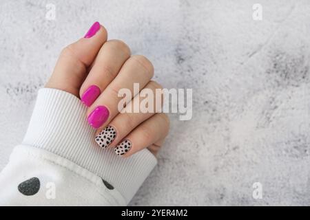 Manicured female hands with stylish pink nails and design. Trendy modern design manicure. Gel nails. Skin care. Beauty treatment. Nail care. Wellness. Stock Photo