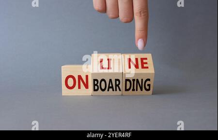 Online Onboarding symbol. Businessman Hand points at turned wooden cubes with words Online Onboarding. Beautiful grey background. Business and Online Stock Photo