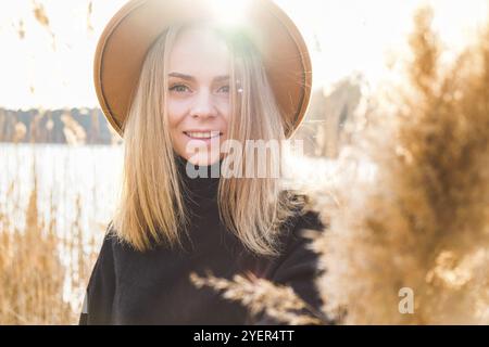 European blonde woman with beige hat in black sweater in the countryside. Golden hour, cottagecore. Local travel. Slow living. Mental health. Earth to Stock Photo