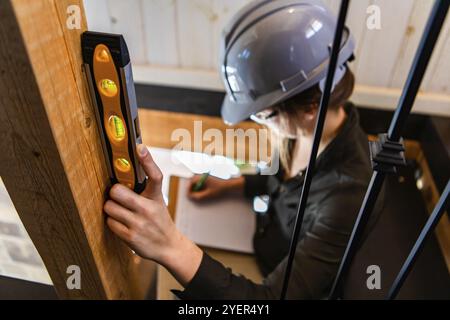 Female construction inspector. selective focus of spirit level on woman's hand, she takes notes on her clipboard during a pre-purchase inspection Stock Photo