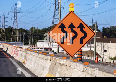 Temporary detour from normal traffic route, three lines road, Temporary condition signs on road cement barriers, work zone in the background Stock Photo