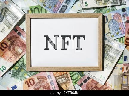 NFT non-fungible token text. Concept words NFT non-fungible token on paper blank. Background of euro bills. Blockchain asset crypto art, digital art, Stock Photo