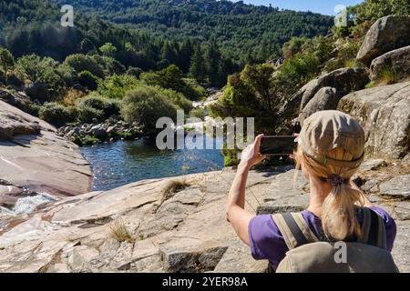 Unrecognisable woman taking a photo of a pond in a riverbed. Stock Photo