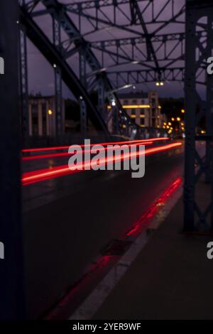 Defocused Lights of cars at night in Krakow bridge. Street line lights. Night highway city. Long exposure photograph night road. Colored bands of red Stock Photo