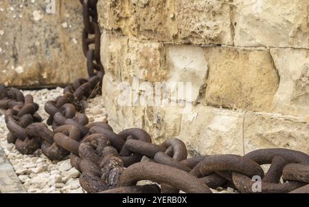A huge, old and rusty chain hanging down from sandstone wall in Fort St. Elmo, Valletta, Malta, Europe Stock Photo